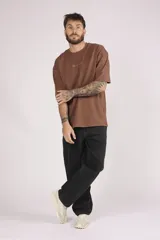 Remera marrón de corte holgado con pequeño logo bordado en el pecho.