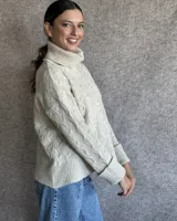 Sweater de lana color crudo con cuello alto y diseño trenzado.