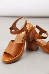 Sandalia de cuero marrón con diseño open-toe, tira ancha en el empeine, correa ajustable con hebilla en el tobillo y tacón ancho de madera.
