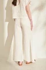 Pantalón negro de lino de tiro alto, con diseño ajustado en las caderas y perneras amplias y acampanadas con paneles insertados que generan mucho vuelo en el bajo.
