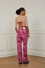 Pantalón jean de corte recto con estampado abstracto en tonos rosa y bordó.