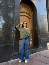 Buzo de cuello bote con diseño de hombro descubierto, confeccionado en tela angorina elastizada. Presenta un corte amplio en la parte superior y ajustado en la cintura, con mangas largas.