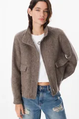 Chaqueta de paño color marrón, con cuello alto, cierre frontal con cremallera y bolsillos laterales con solapa.