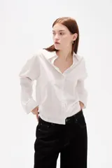 Camisa de algodón con diseño de rayas verticales finas, cuello clásico, cierre frontal con botones y mangas largas con puños abotonados.