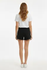 Short de jean negro de tiro alto, con diseño de cinco bolsillos, detalles de roturas y ruedo deshilachado.