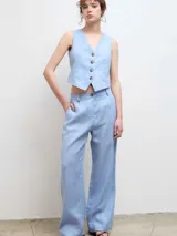 Pantalón de vestir de corte recto y tiro medio, confeccionado en tela de lino color celeste, con cierre frontal y bolsillos laterales.