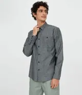 Camisa de manga larga gris con textura, cierre con botones, cuello clásico y bolsillo en el pecho.