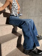 Pantalón de jean azul de corte acampanado con costuras verticales en el frente.