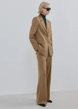 Pantalón de vestir tostado, de corte recto y tiro medio, con bolsillos laterales y cierre frontal.