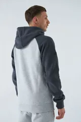 Buzo canguro gris con mangas ranglan azul marino, capucha con cordones ajustables y bolsillo delantero. Estampado frontal con el logo de la marca y el año de fundación.