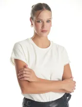 Blusa de crepe color blanco, con cuello redondo y mangas cortas. Presenta apliques de perlas decorativas en el borde del cuello y en los extremos de las mangas.