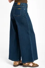 Pantalón jean de corte wide leg, tiro alto y color azul oscuro, con diseño clásico de cinco bolsillos y costuras en contraste.