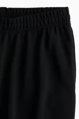 Pantalón negro de corte ancho, con cintura elástica y bolsillos laterales.