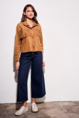 Camisa color camel de gamuza sintética, corte al cuerpo, con flecos en el pecho y mangas largas.