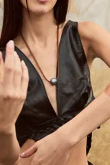 Collar con dije esférico color gris plomo y cordón fino de cuero marrón.