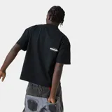 Camiseta negra de corte holgado con estampado frontal del logo "emestudios" en blanco con contorno negro y líneas horizontales en rojo, azul y blanco. Debajo del logo, la frase "ALWAYS GRATEFUL".