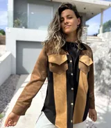 Sobre camisa de gamuza con diseño de paneles verticales en colores marrón, tostado y negro. Presenta cuello clásico, cierre frontal con botones metálicos y un bolsillo en el pecho con solapa.