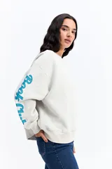 Buzo de algodón color gris claro, con cuello redondo, corte holgado y diseño de estampa en color azul en la manga derecha.