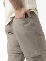 Pantalón técnico Merrell de trekking, color beige, desmontable con cierre para convertirlo en bermuda. Posee cintura con cinturón ajustable y bolsillos con cierre.