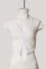 Remera de tejido acanalado color beige, con escote en V profundo decorado con puntilla de encaje en los bordes, mangas cortas y diseño abierto en el frente.