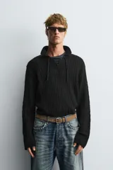 Polo de punto negro con diseño de estructura abierta, cuello solapa y cierre frontal ajustable mediante cordones. Presenta mangas largas y terminaciones en rib.