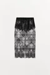Falda midi semitransparente de tiro medio, confeccionada en tejido de encaje negro con detalle de superposición en la cintura y ajuste con lazada. Presenta bajo acabado en ondas y abertura en la espalda.