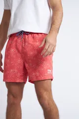 Short de baño con cintura elástica y cordón ajustable, confeccionado en tela ligera de secado rápido. Presenta un estampado botánico integral en tonos amarillos, blancos y azules, con dos bolsillos delanteros y uno posterior.