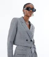 Blazer corto con estampado de pata de gallo en blanco y negro, con cuello solapa, cierre cruzado con botones y bolsillos delanteros simulados.