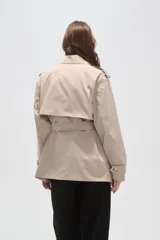 Trinchera de corte corto y diseño clásico, confeccionada en poliéster color negro. Presenta solapas amplias, cierre frontal cruzado con lazo ajustable en la cintura, charreteras en los hombros y puños con trabillas.