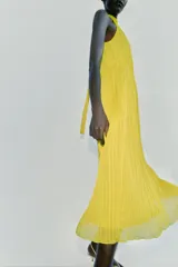 Vestido midi amarillo con diseño plisado, cuello halter y cintura elástica.