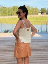 Musculosa marrón de gamuza con bordados blancos en el frente y detalle de flecos en los hombros. Tiene cuello redondo y sisas amplias con terminación de crochet.