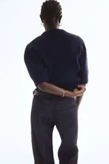 Top de punto acanalado en color azul marino, con cuello redondo, mangas cortas abullonadas y terminaciones acanaladas en puños y ruedo.