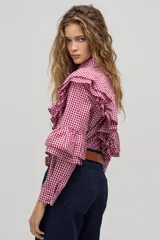 Camisa de manga larga con estampado de cuadros vichy en color rojo y blanco. Presenta cuello clásico, cierre frontal con botones de nácar y volados dobles decorativos en el frente, espalda y mangas.