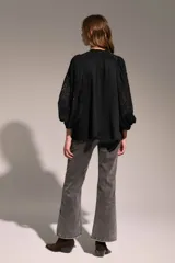 Camisa negra de corte holgado con cuello mao y escote en V. Presenta detalles de encaje en el cuello y en las mangas abullonadas de largo tres cuartos.