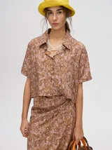 Camisa crop de manga corta con cuello camisero y cierre frontal de botones. Confeccionada en viscosa con un estampado abstracto único en tonos marrones y rosados.