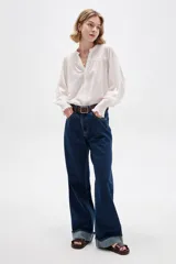 Pantalón de jean azul oscuro, de corte recto y tiro alto, con botamanga rebatida.