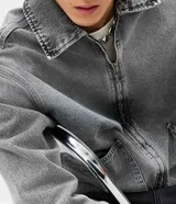 Campera de jean para hombre de corte boxy, con lavado gris de efecto desgastado, cuello camisero, cierre frontal con cremallera y bolsillos delanteros.