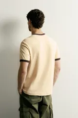 Camiseta regular fit gris melange con cuello redondo y mangas cortas. Presenta acabados con rib en contraste de color marrón oscuro en el cuello y los puños.