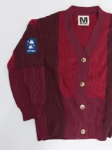 Cardigan oversize de tejido de punto grueso con diseño de bloques de color en tonos beige y marrón. Presenta cuello en V, cierre frontal con botones, mangas largas abullonadas y parches decorativos en el pecho y el hombro.