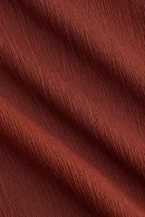 Top sin mangas de punto elástico texturizado, color marrón, con escote bote y frunces laterales que generan un leve efecto drapeado.