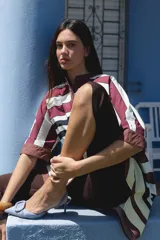 Camisa blanca de corte oversize y largo midi, confeccionada en algodón. Presenta cuello mao, cierre frontal oculto por tapeta y mangas cortas con dobladillo. Incluye un pequeño bordado de una flor en el pecho.