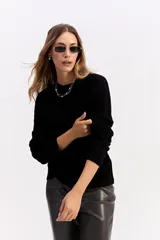 Buzo de punto negro con diseño de trenzas en relieve, cuello redondo y mangas largas.