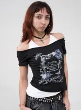 Remera negra con diseño ajustado de manga corta y escote off-shoulder, que incluye un detalle superpuesto simulando una bikini blanca por debajo. Posee estampado gráfico al frente con motivos florales y texto.