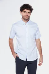 Camisa de manga corta color celeste claro, con cuello abotonado (button-down) y un bolsillo de parche en el pecho.