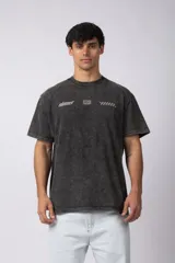 Remera negra con efecto acid wash, corte holgado y estampa frontal con logos y diseño de automovilismo.