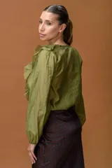 Camisa de color verde oliva con volados en el escote en V y mangas largas con puños elásticos.