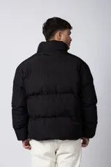 Campera puffer de corte relajado en color verde oscuro, con cuello alto, cierre frontal completo y logo bordado en el pecho.
