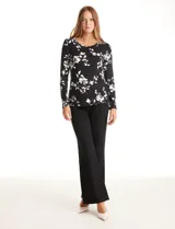 Remera de modal estampada con flores blancas sobre fondo negro, de manga larga y cuello redondo.