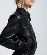 Campera de cuero sintético (PU) color negro, con cuello inglés, cierre frontal por cremallera y bolsillos laterales con cierre en el pecho. Presenta un diseño regular con mangas largas.
