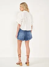 Short de jean azul con tachas doradas, tiro alto y ruedo doblado.